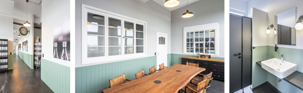 Ein Büro im Industrial Look mit einem grünen Wandsockel und historischen Fenster- und Tür-Elementen. Im Bild ganz rechts das passende Firmen-WC mit grünem Farbsockel und dunkelgrauen Akzenten.