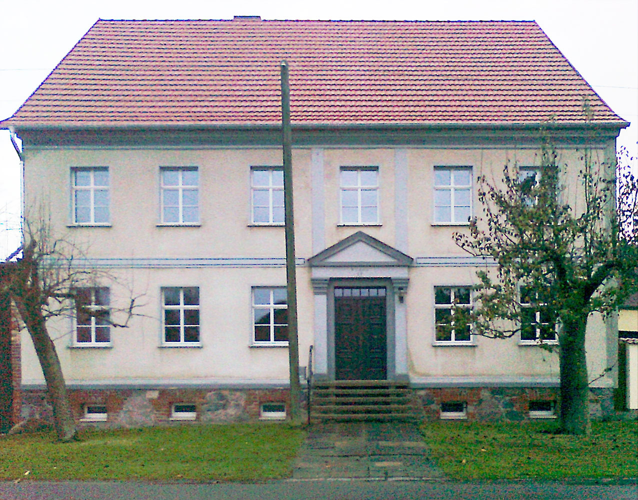 Bauernhaus Frontansicht nachher mit unterilten weißen Fenstern mit Wiener Sprossen, neuem Dach mit roten Dachziegeln und nachgebauter Eingangstür.
