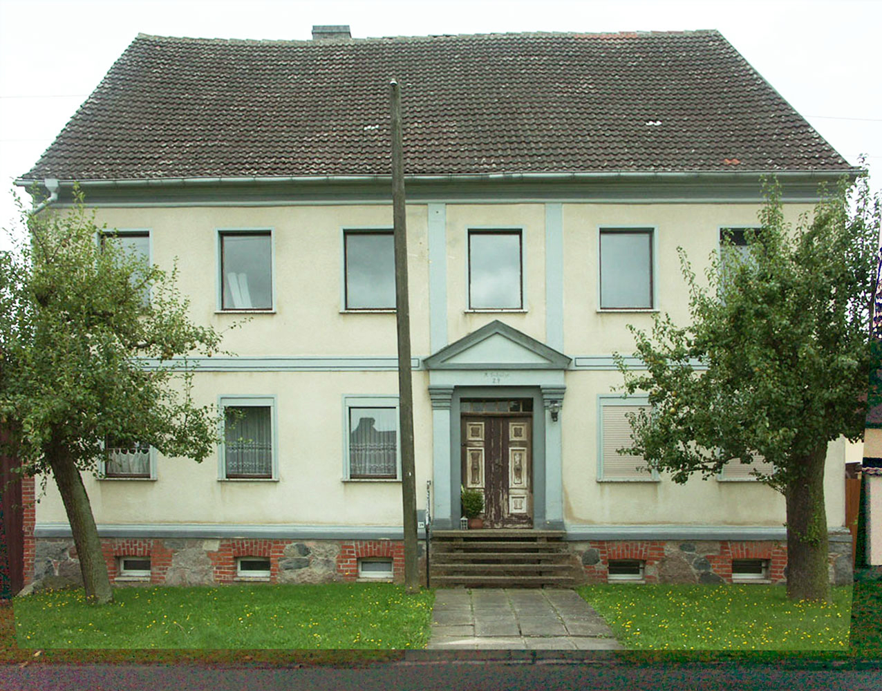 Bauernhaus Frontansicht vorher mit sprossenlosen braunen DDR-Fenstern und Dach mit Betonsteinen.