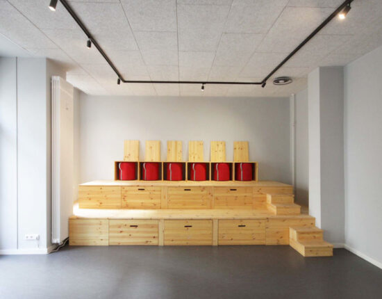 Holztribüne mit schubladen und verstauten roten Polsterhockern.