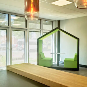 Ein Raum mit einer grün gepolsterten Sitzinsel mit Dach. Im Bild auch 2 bronzefarbene Pendelleuchten.
